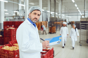 Inspector holding clipboard during a supplement facility inspection in a production area.