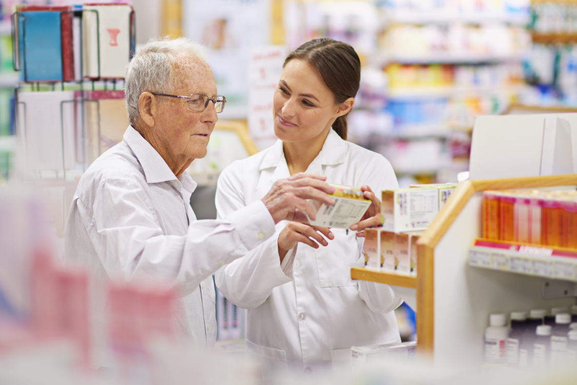 Pharmacist helping elderly customer choose dietary supplements at a retail store.