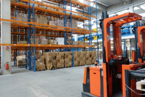 Warehouse of a supplement contract manufacturer with stacked boxes and forklifts ready for product storage and distribution.