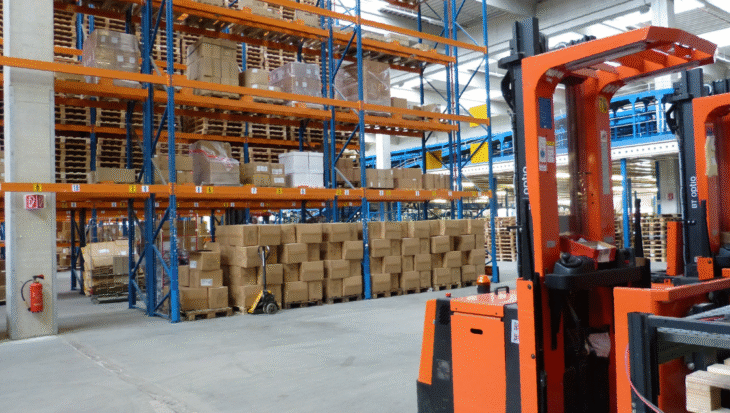 Warehouse of a supplement contract manufacturer with stacked boxes and forklifts ready for product storage and distribution.