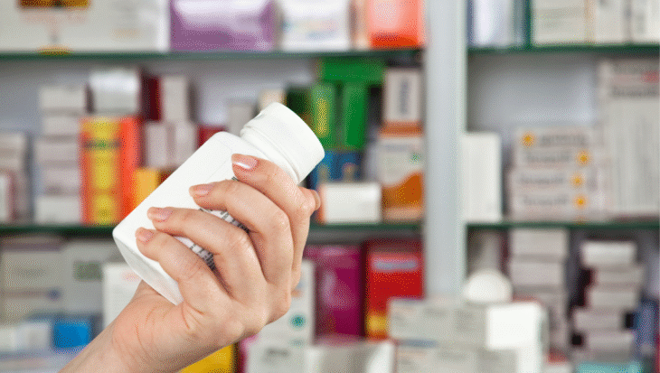 A hand holding a supplement bottle in a pharmacy setting, highlighting the importance of verified certifications.