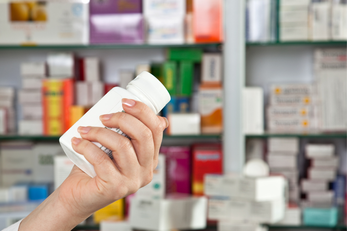 A hand holding a supplement bottle in a pharmacy setting, highlighting the importance of verified certifications.