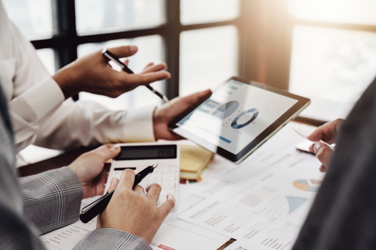 Business professionals reviewing graphs and metrics on a tablet during a strategic buyer outreach meeting