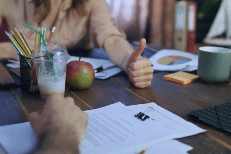 Client giving thumbs up at table with business sale documents, apple, and charts