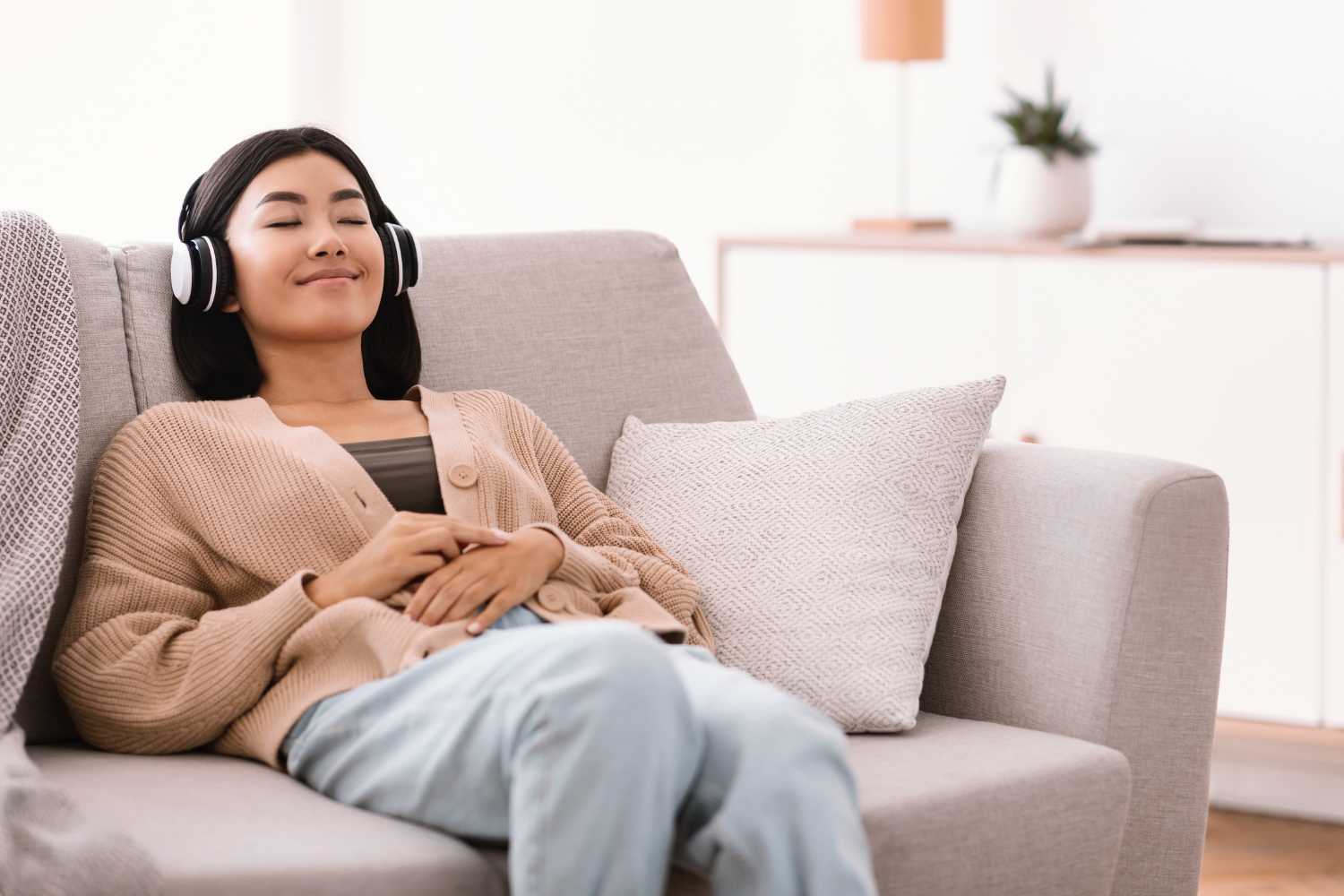 Woman looking calm while listening to music and relaxing on a couch.