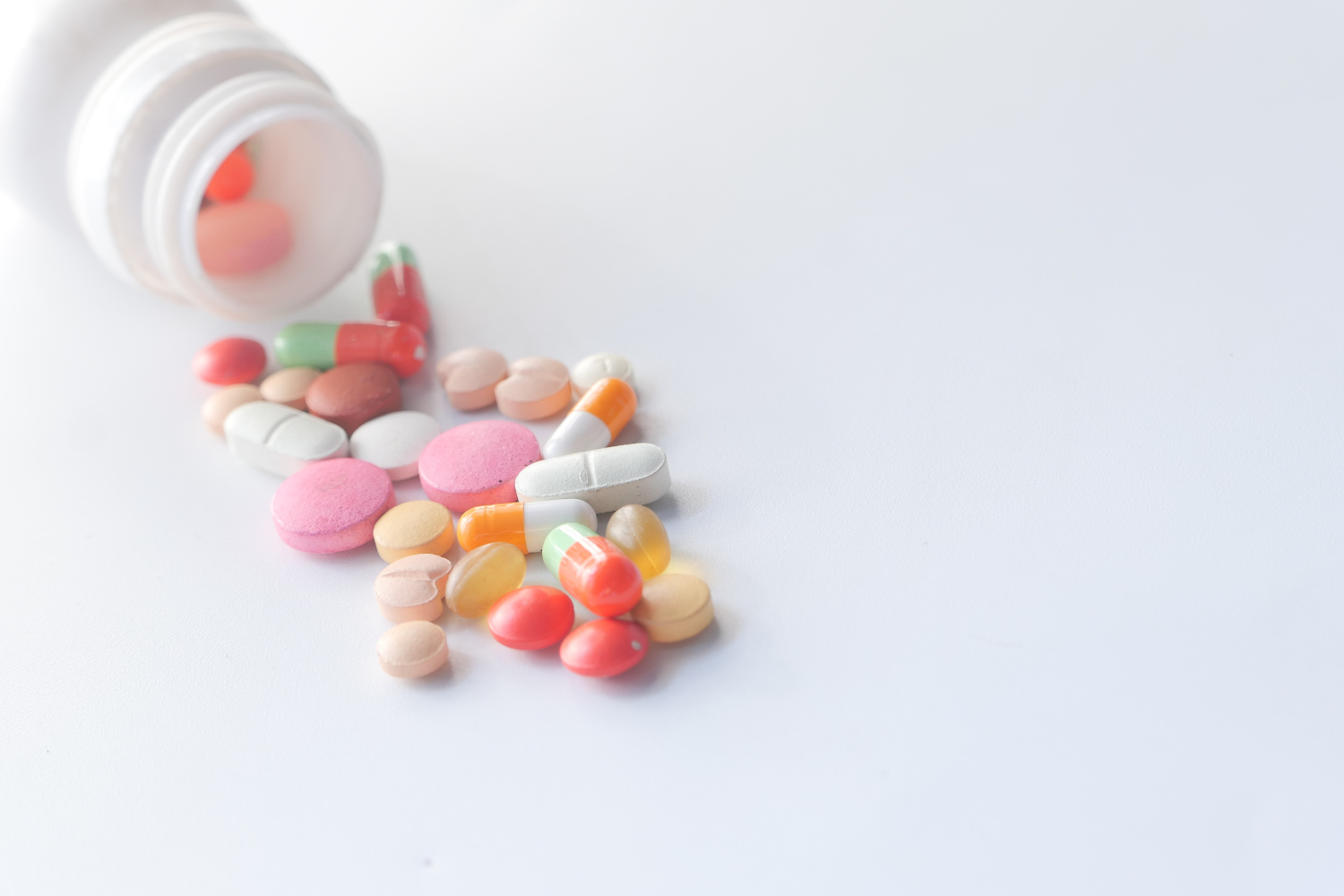 Supplement bottle spilling supplements in different shapes and colors.