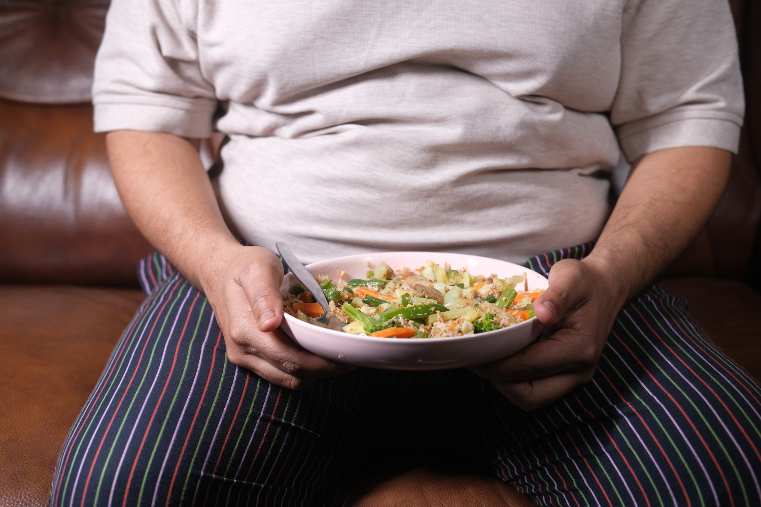 Heavy-set person holding a bowl of salad.