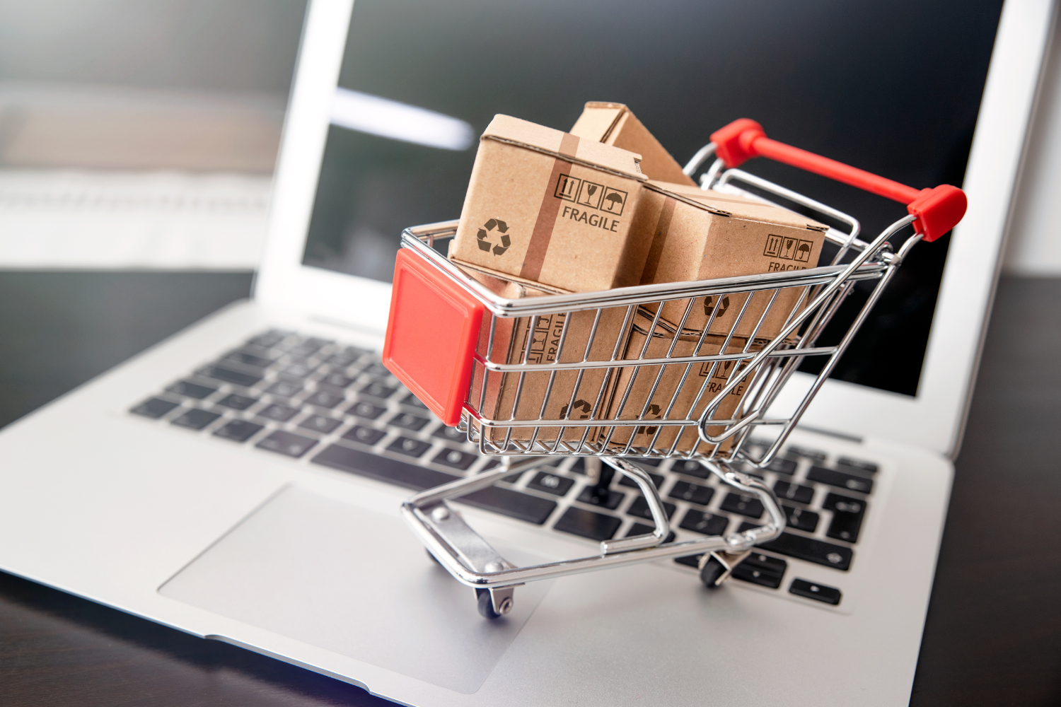 Laptop with shopping cart, signifying online shopping.