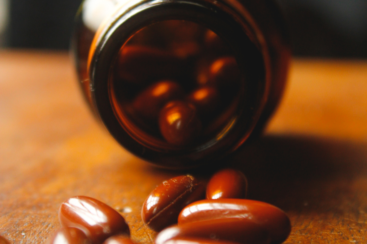 Capsules spilling from brown supplement bottle.