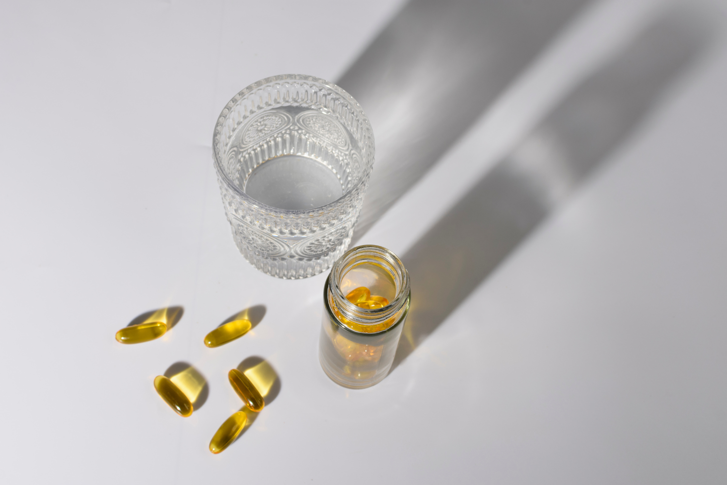 A glass of water with yellow capsules.
