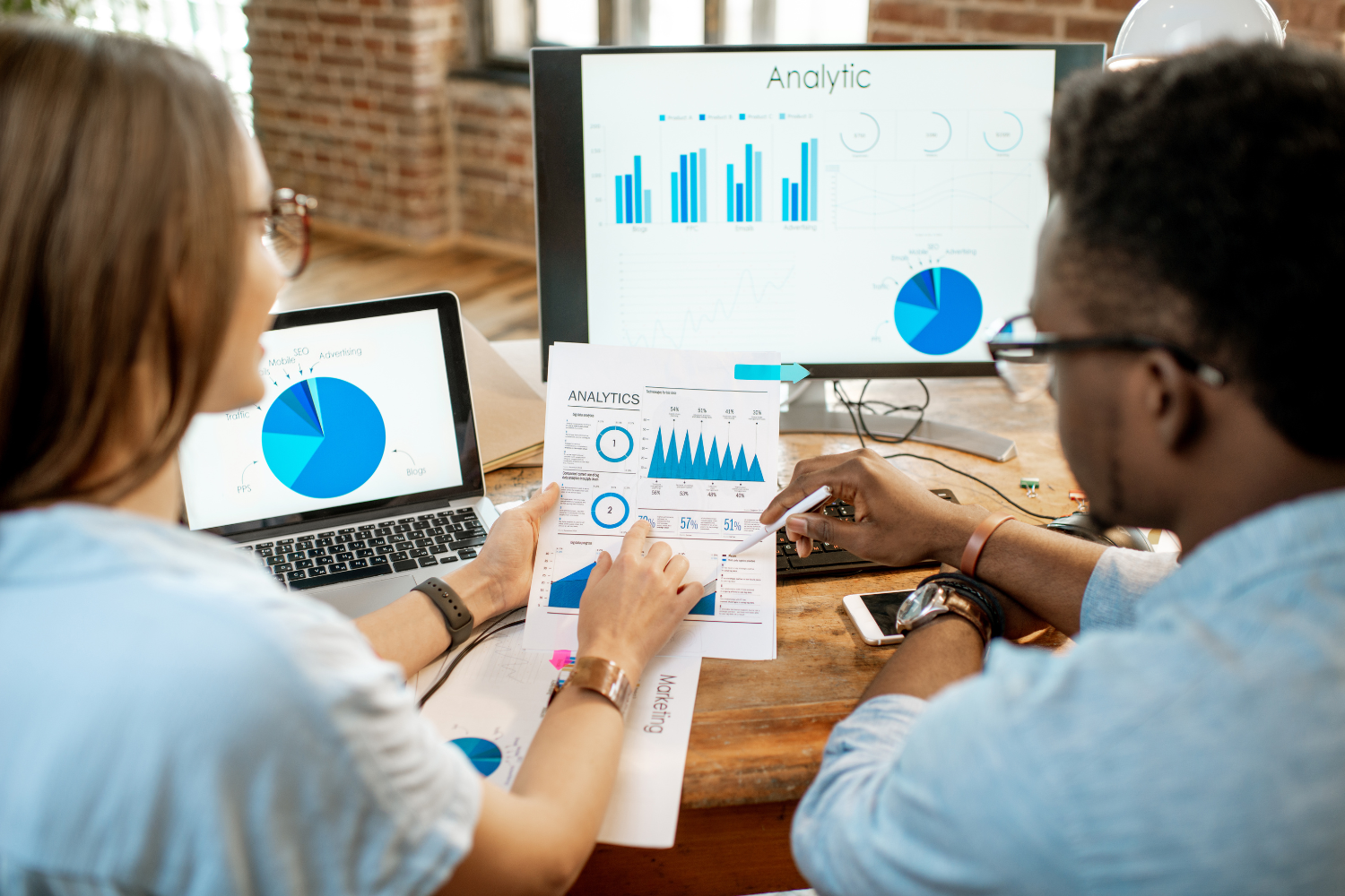 Two people analyzing sales data on a computer screen.