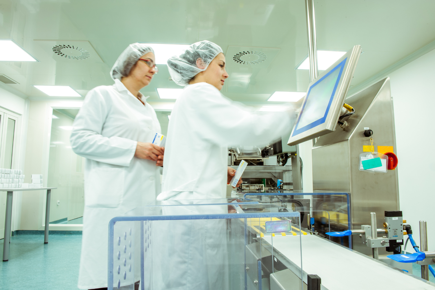 A state-of-the-art manufacturing plant with workers in clean suits inspecting machinery.