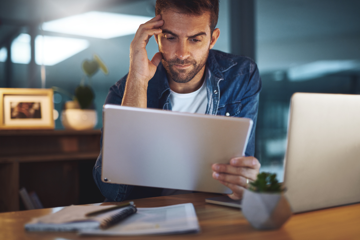 Man looking uncertain while checking his tablet.