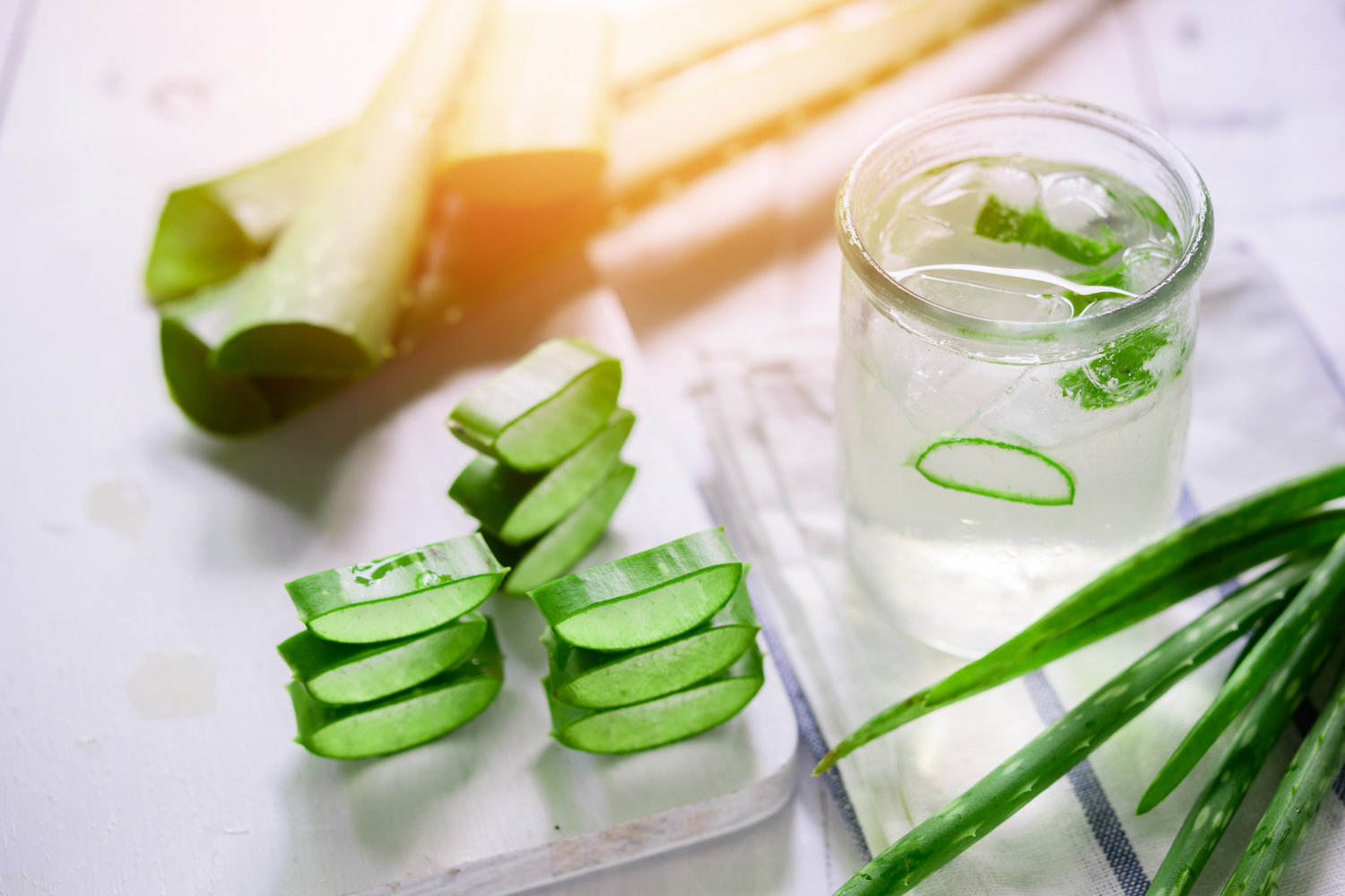 Slices of aloe vera and glass of water with aloe vera in it.
