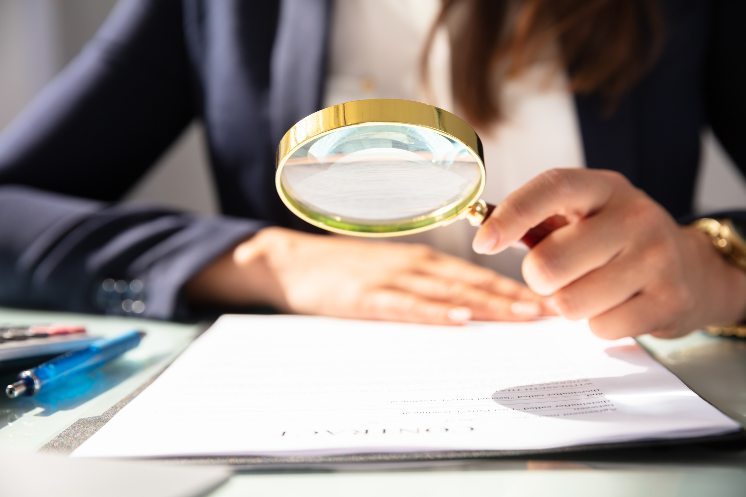 A magnifying glass hovering over a contract.