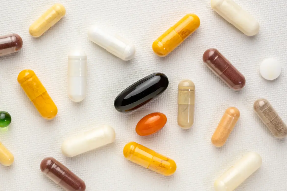 Various types of dietary supplement capsules in different colors and formats on a white background