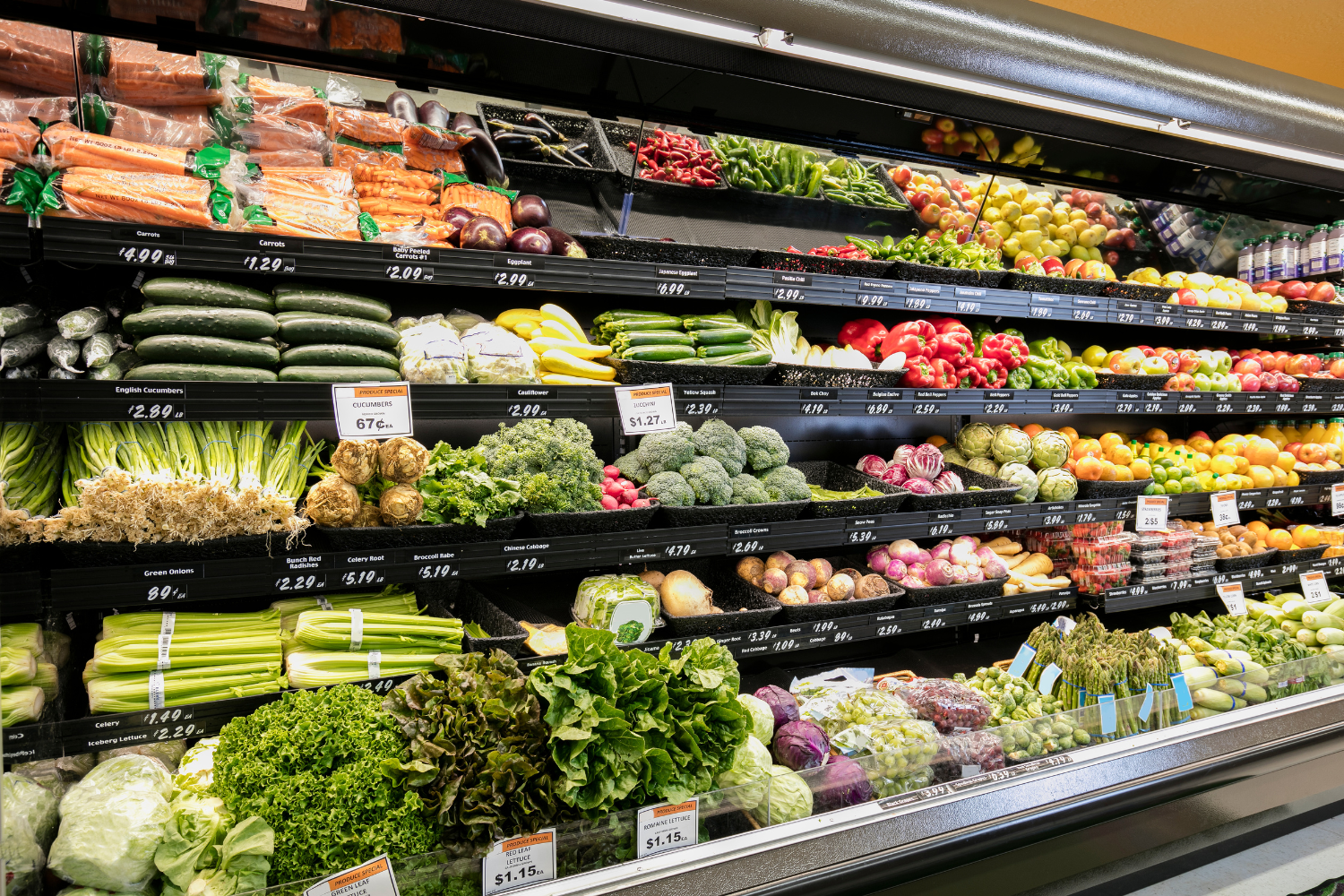 Grocery store aisle with vegetables and fruits.