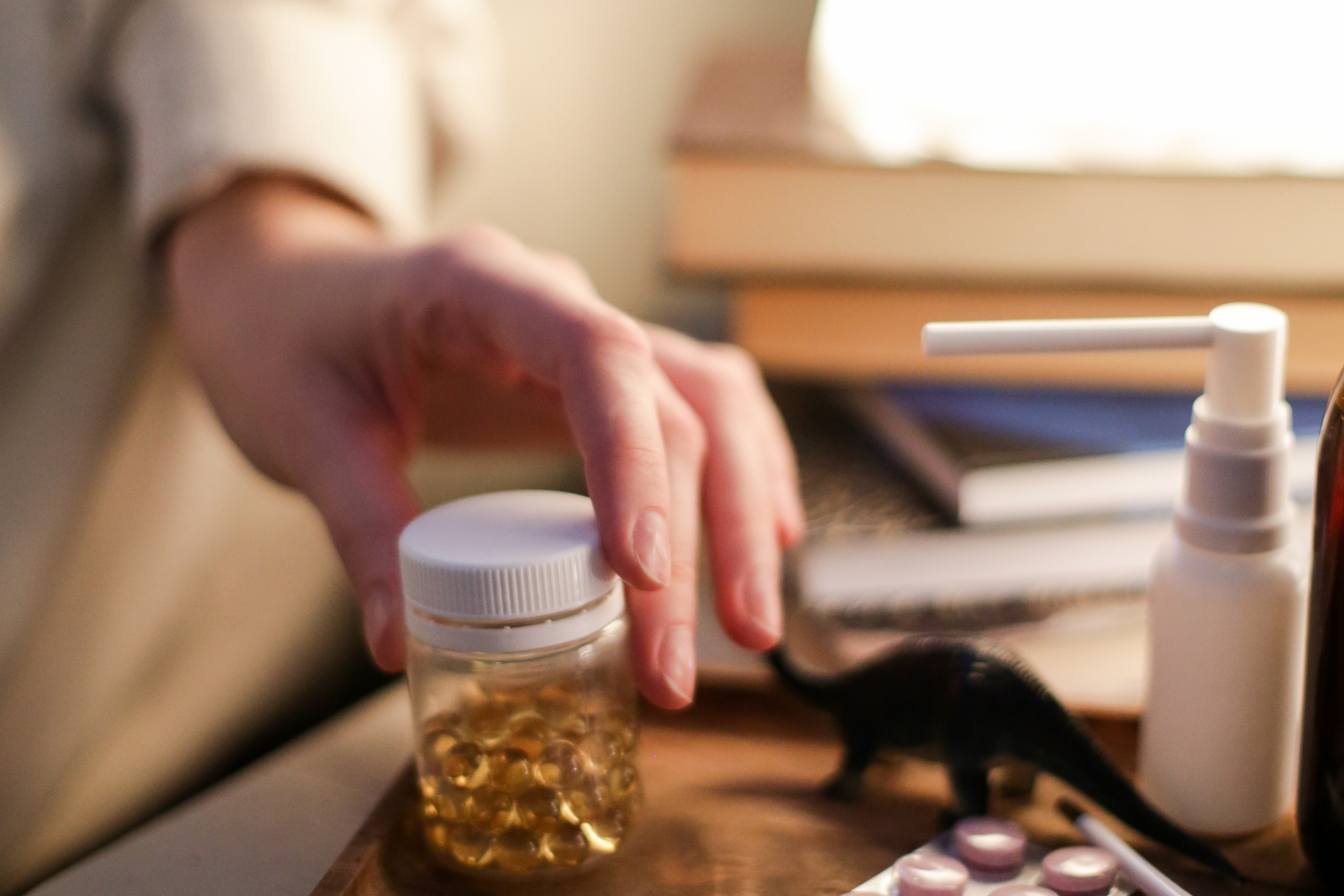 Person reaching for supplement bottle on the night stand.