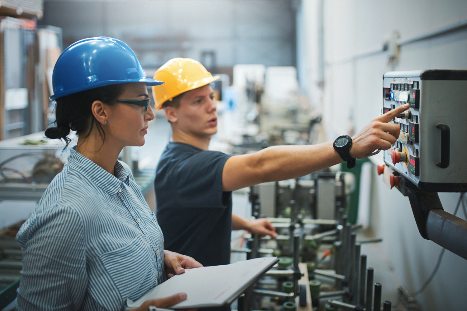 A manufacturing facility with facility workers checking a machine.