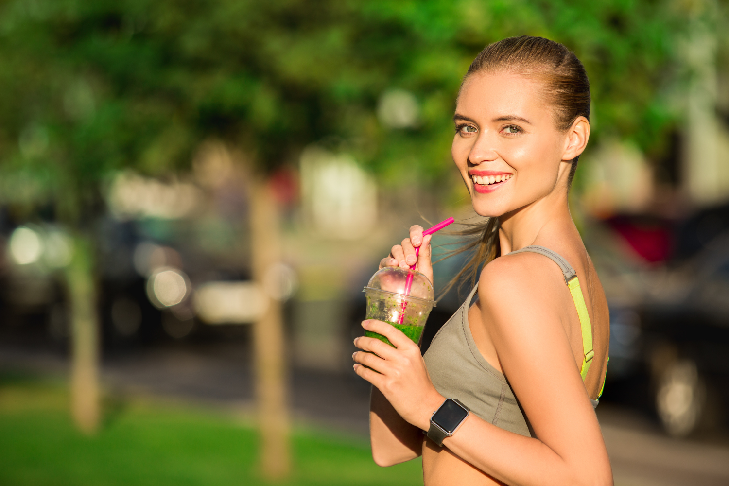A woman drinking a detox drink at the park.