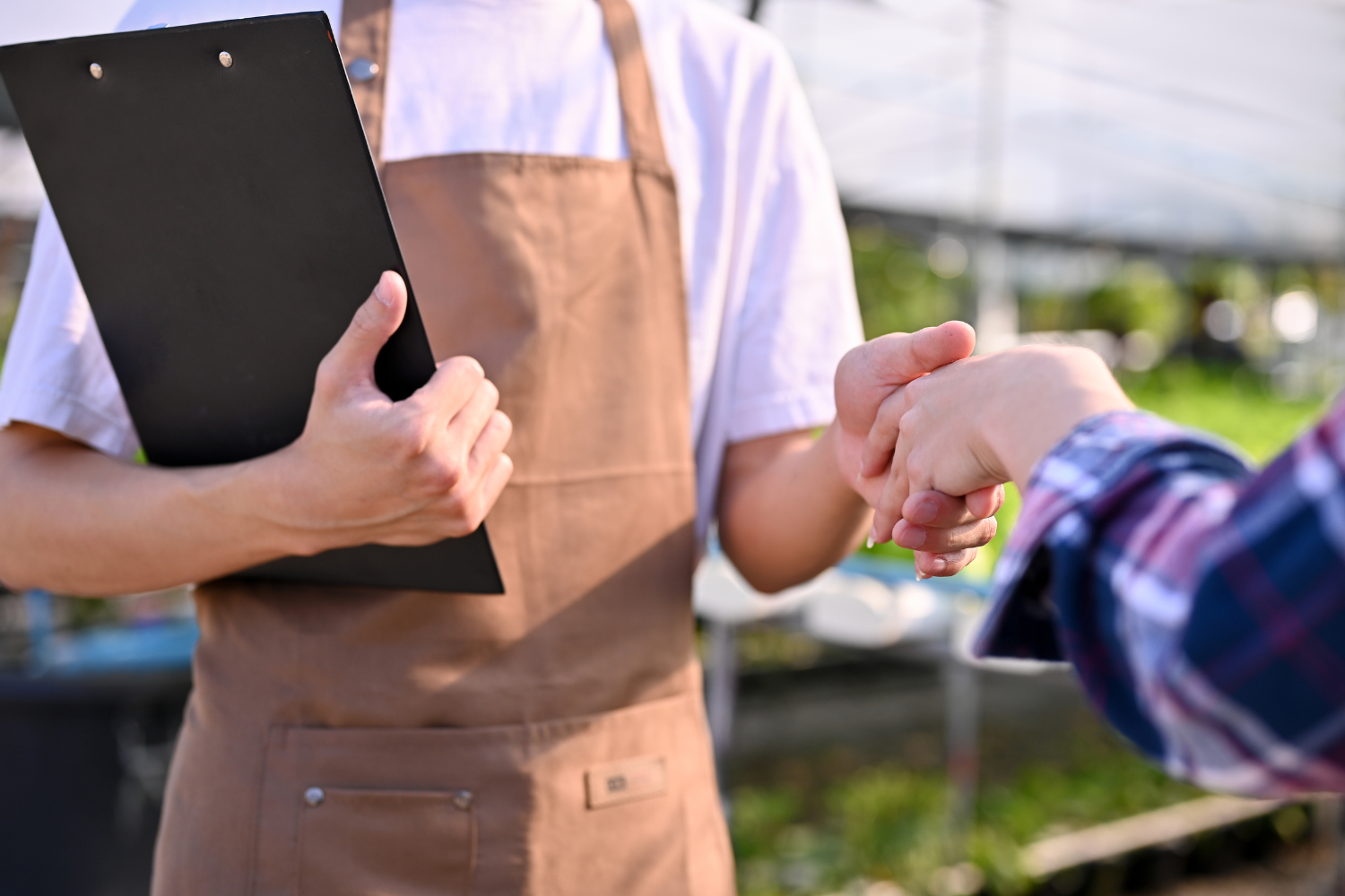 Two people shaking hands, one holding a clipboard.