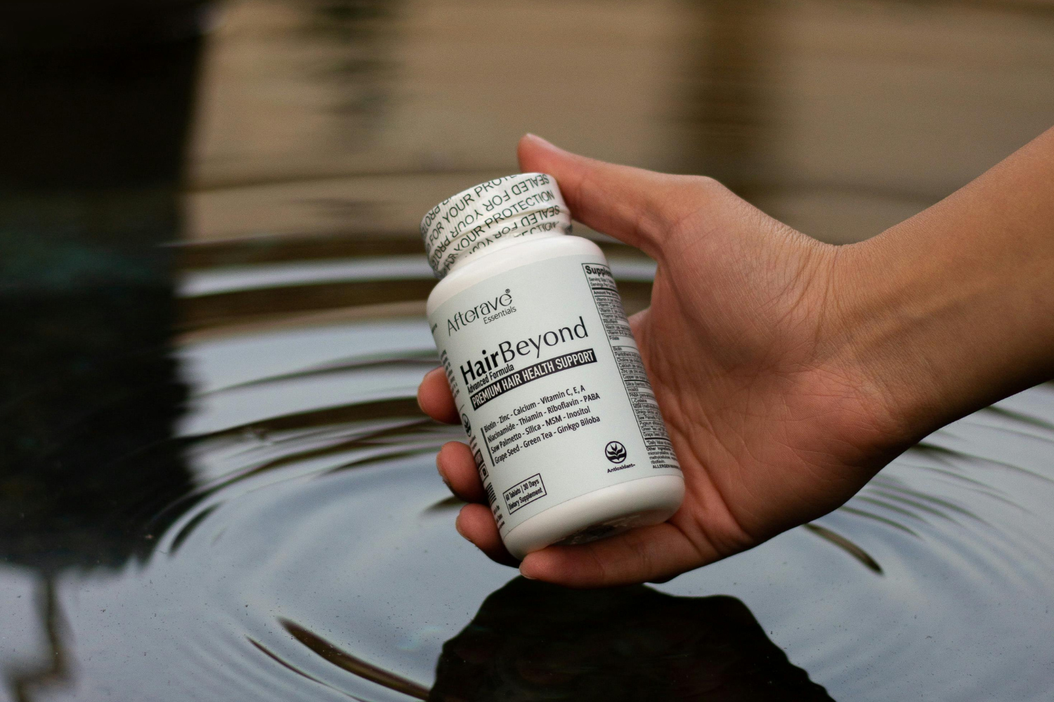 Hand holding supplement bottle with induction seal.