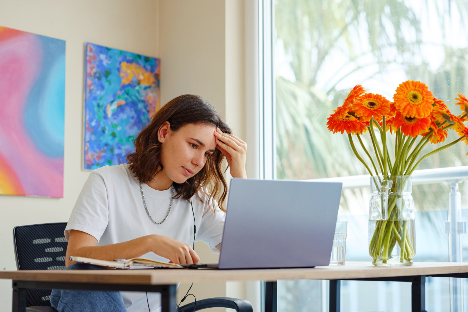 A professional woman working on a laptop, looking stressed.
