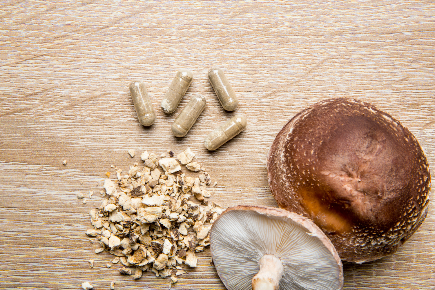 Mushroom and mushroom supplements on a wooden surface.