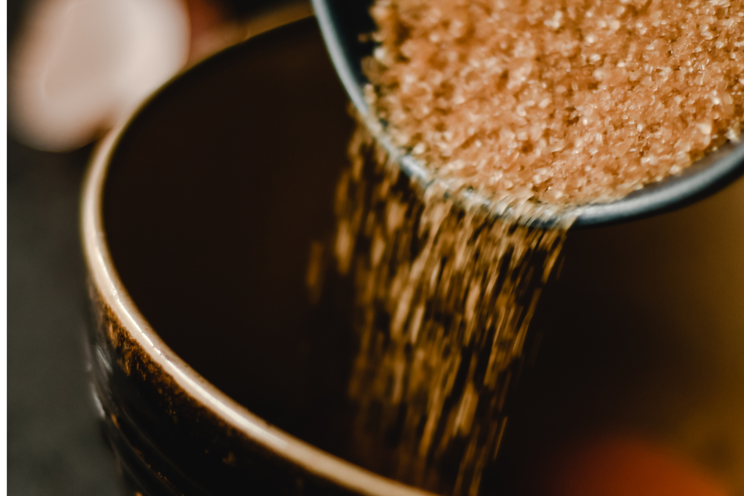 Close-up of brown sugar being poured in a bowl.