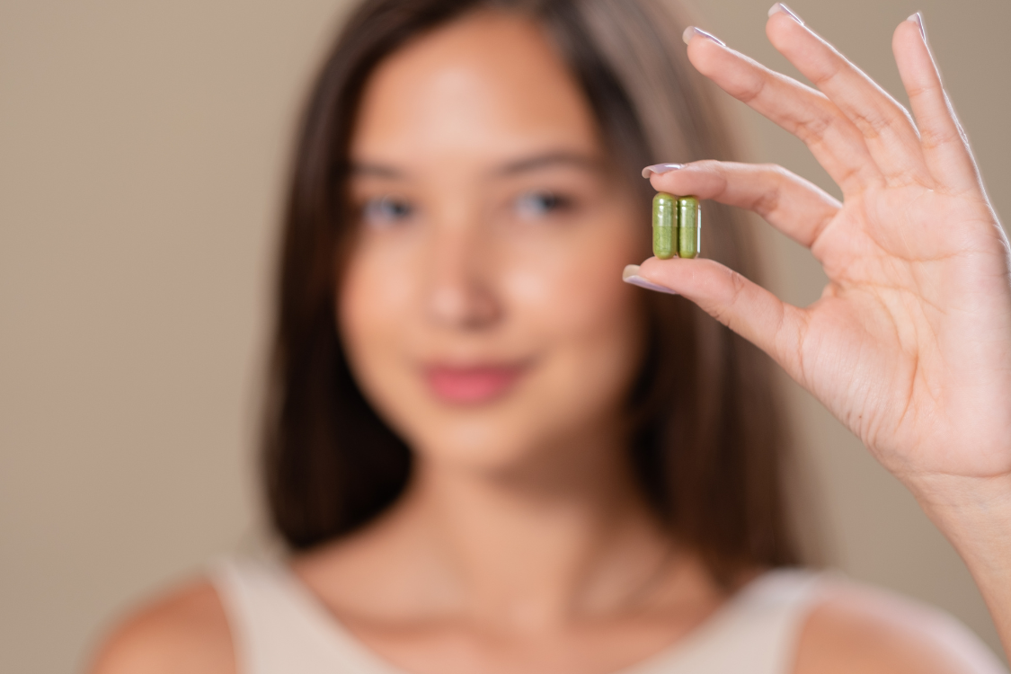 Woman holding green supplement capsules close up for product quality showcase