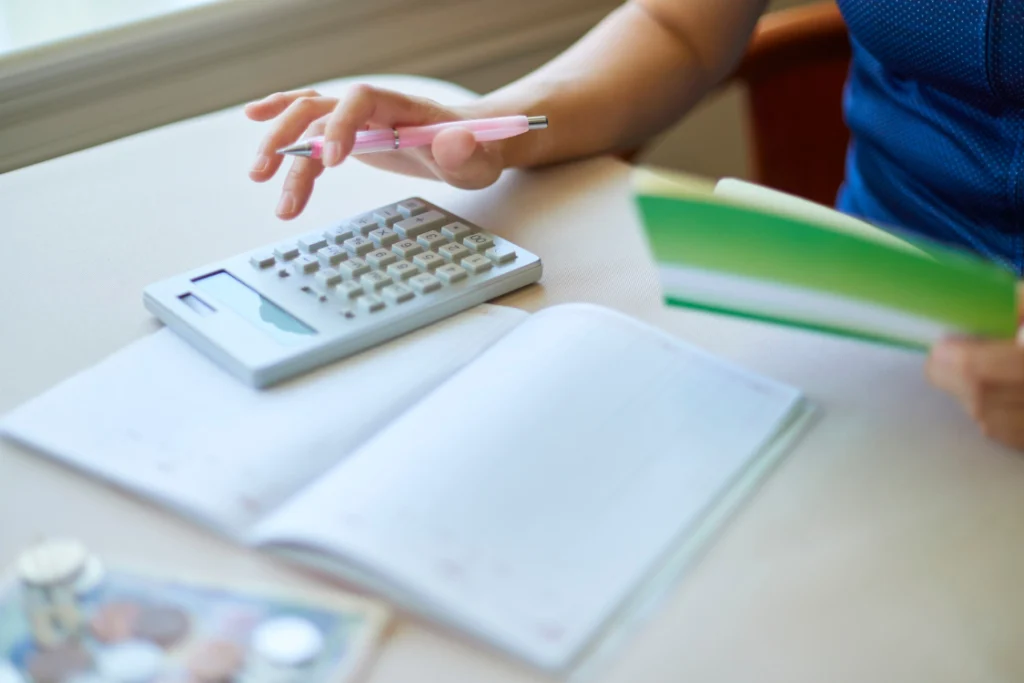 Hand holding a notebook beside a calculator for budgeting with a switch manufacturer cost savings calculator.