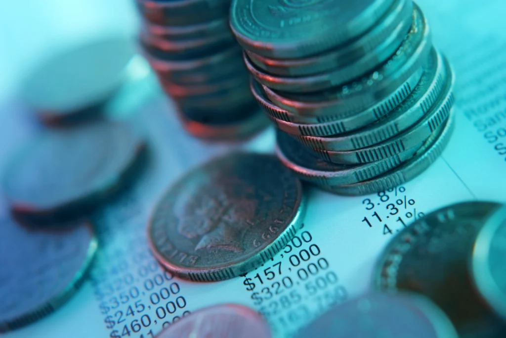 Stacks of coins on a financial report symbolizing money saved with a switch manufacturer cost savings calculator.