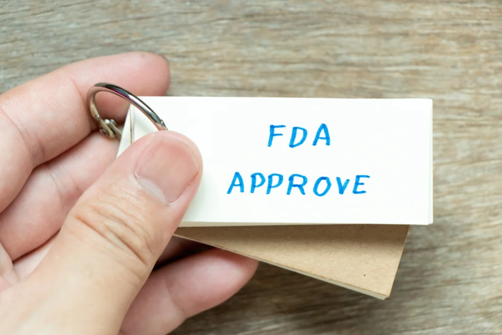 Hand holding a label that says FDA approve, representing compliance and regulatory approval in supplement manufacturing.