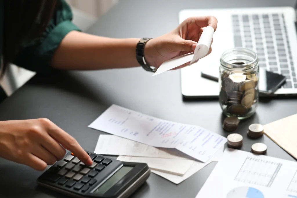 Person using a calculator with receipts to estimate savings in a switch manufacturer cost savings calculator.