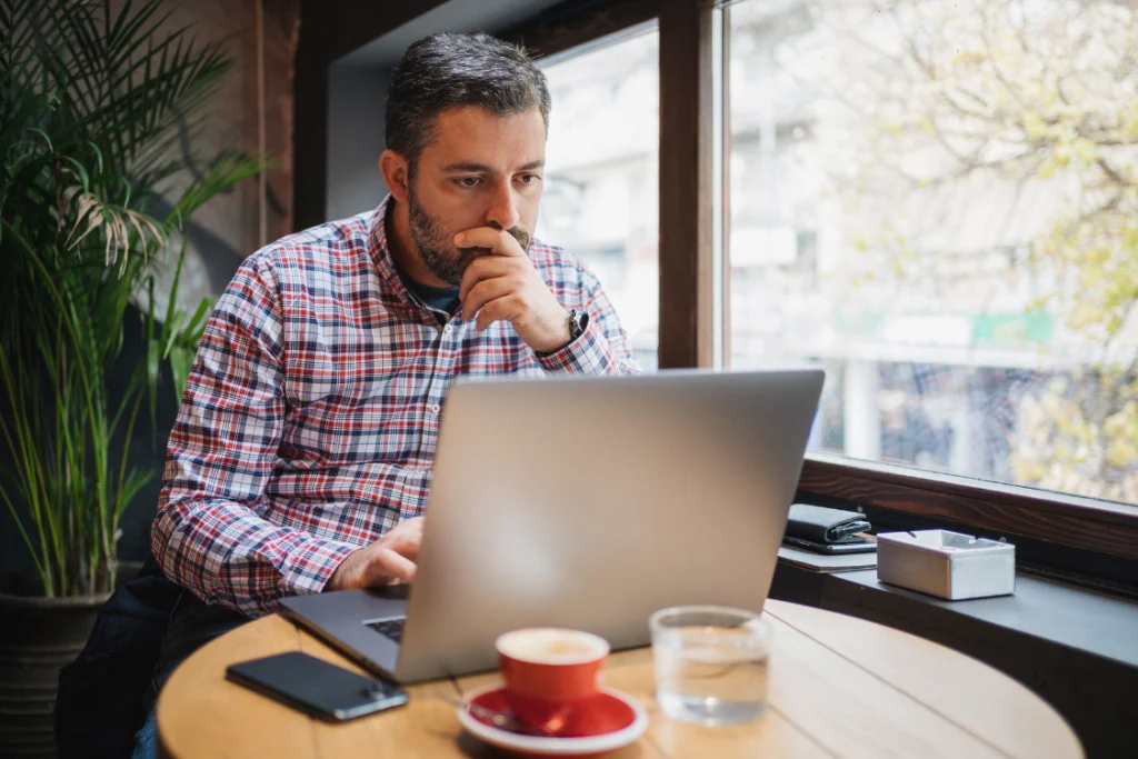 Business owner reviewing supplement manufacturer background information on laptop