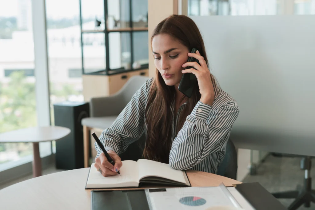 Woman consulting with a supplement manufacturer on the phone while taking notes.