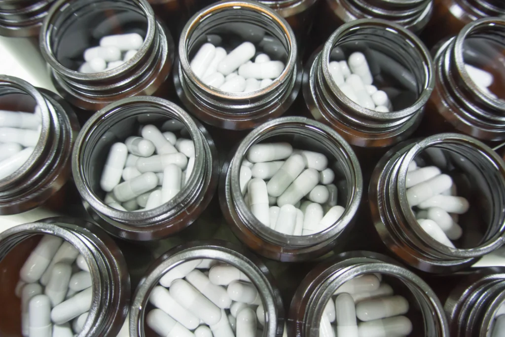 Capsules in bottles representing supplement manufacturer financial stability and production