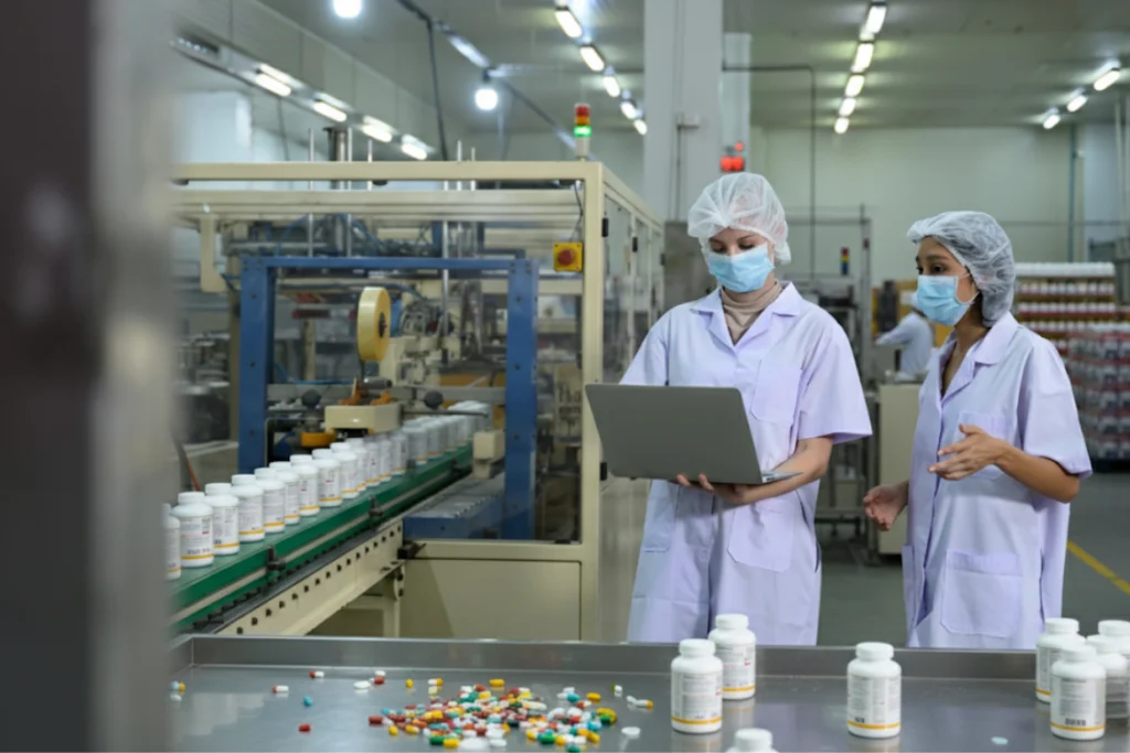Workers at a supplement manufacturer facility checking product quality certifications on production line.
