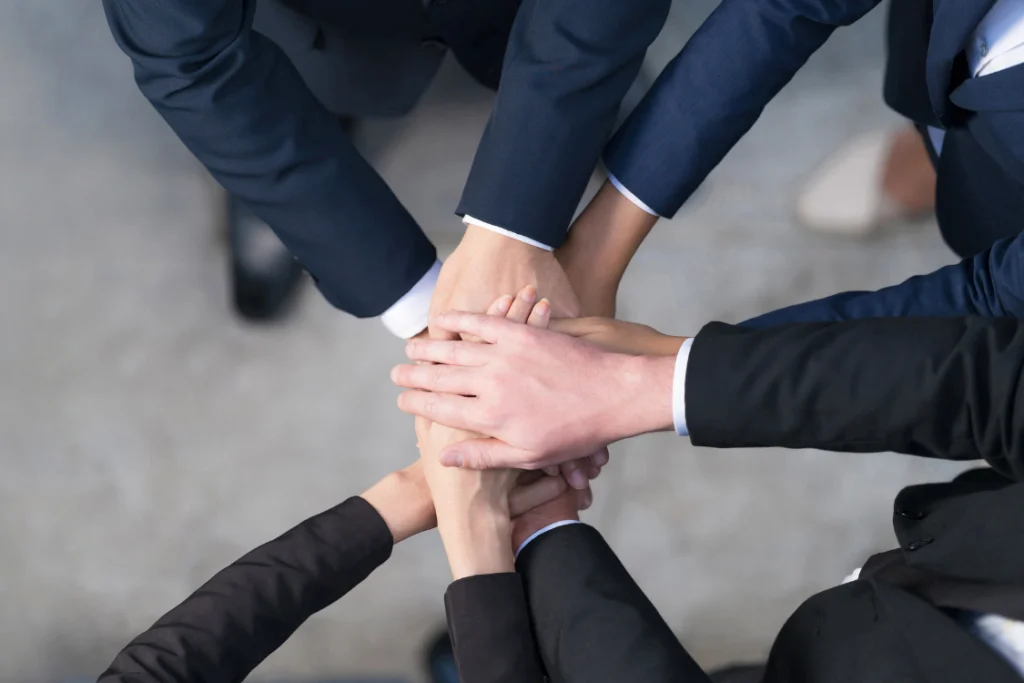 Group of professionals stacking hands showing unity in supplement business ownership structure