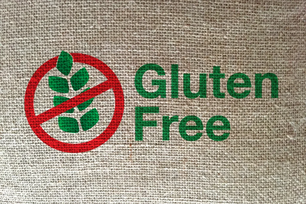 Graphic of a red prohibition circle over green plant leaves next to the text "Gluten Free" on a woven burlap texture, signifying a strict gluten testing protocol by a supplements manufacture.