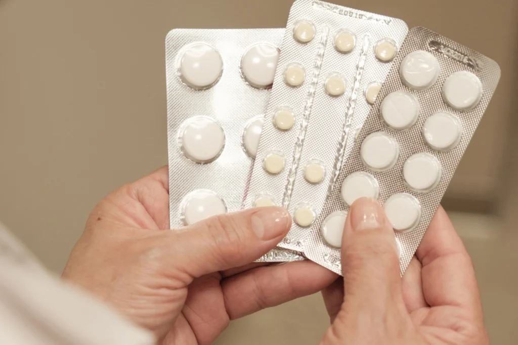 Two hands holding blister packs of pills, symbolizing the supplement products affected by regulatory compliance.