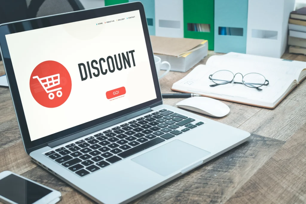 A laptop screen displaying a web page with a shopping cart icon and the word "DISCOUNT," representing the online aspect of securing supplement manufacturing volume discounts.