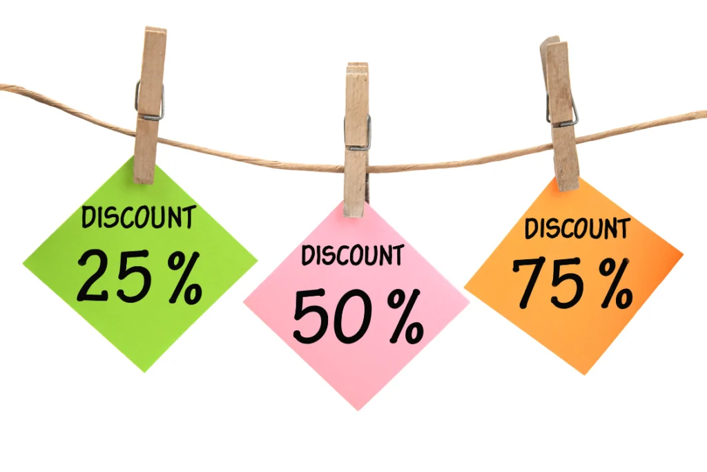 Three colorful sticky notes clipped to a string showing various price reduction tiers: 25%, 50%, and 75% DISCOUNT, symbolizing supplement manufacturing volume discounts and price breaks.