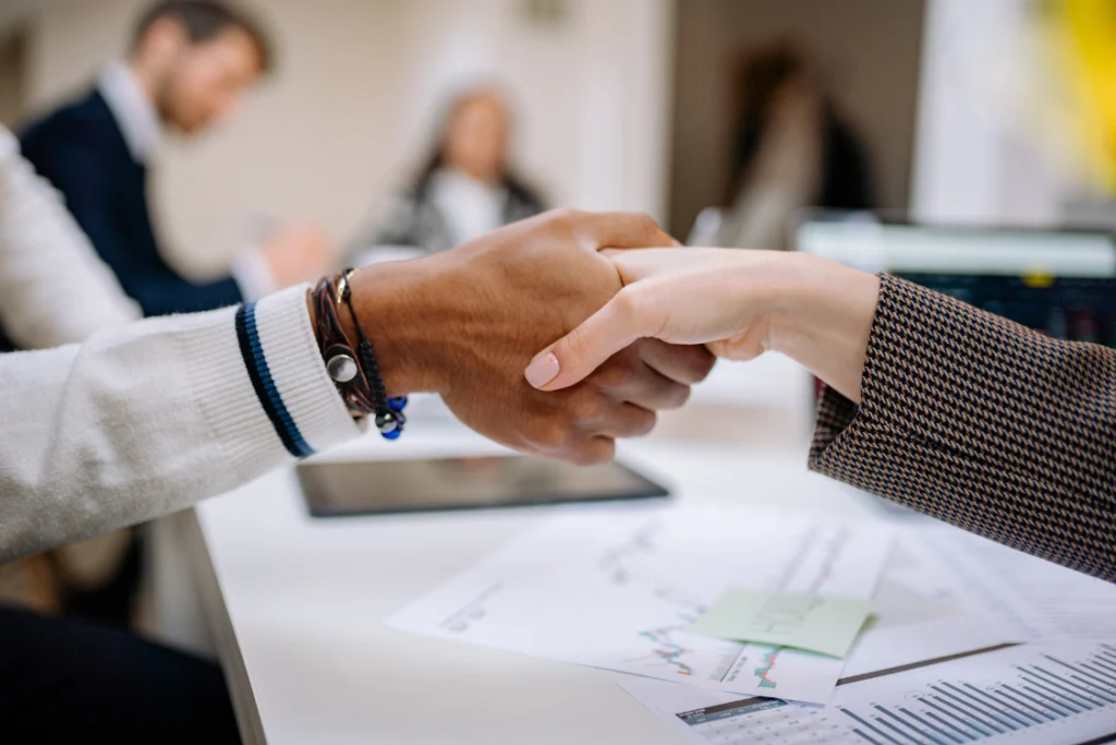 Two business professionals shaking hands over a contract, symbolizing supplement manufacturer price stability and partnership.