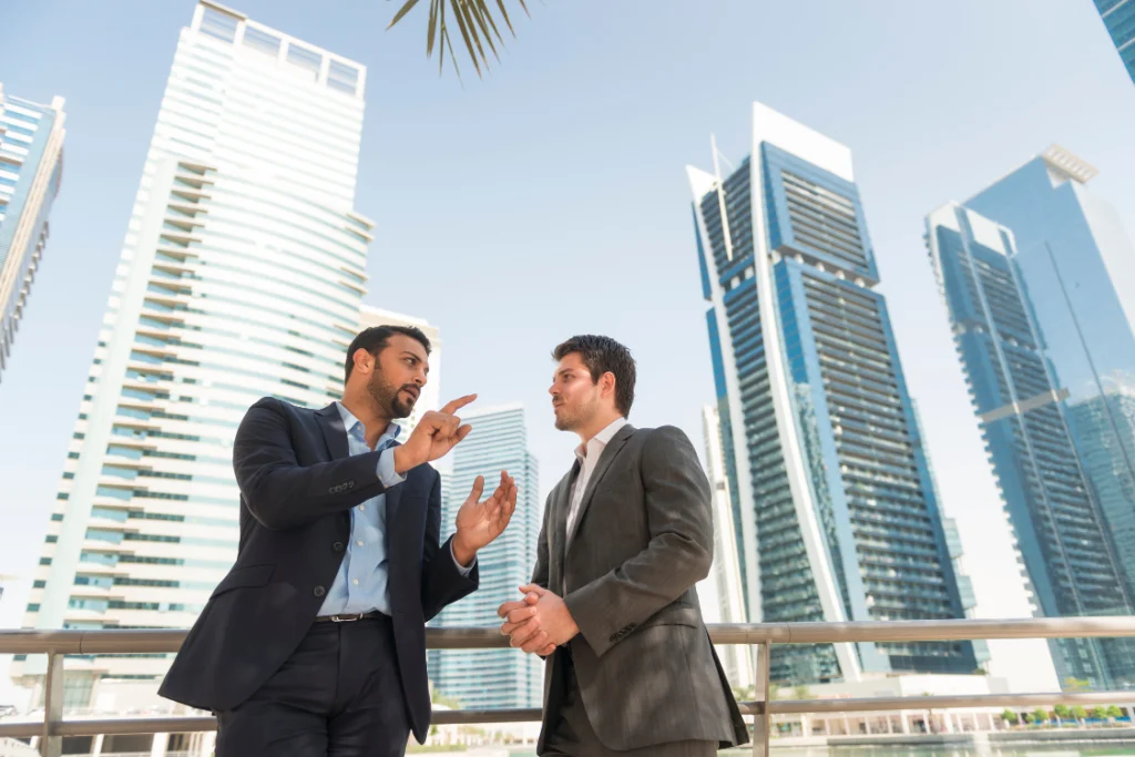 Two business professionals discussing supplement manufacturer pricing comparison strategies against a modern city skyline.