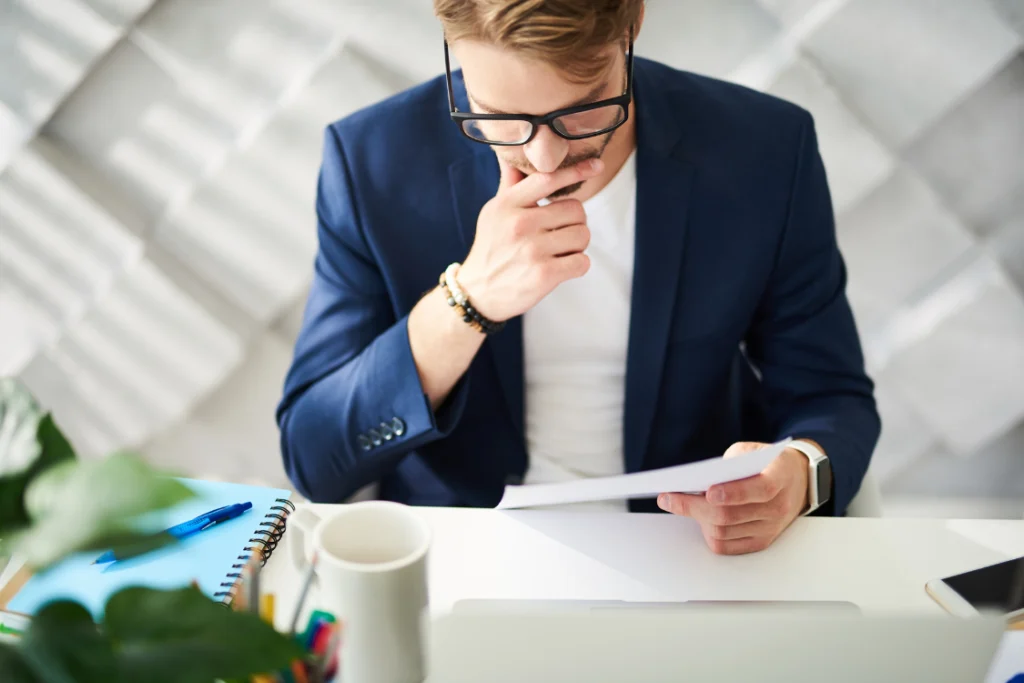 Supplement brand founder in a blue suit and glasses reviewing a contract related to supplement manufacturer pricing and MOQ details.