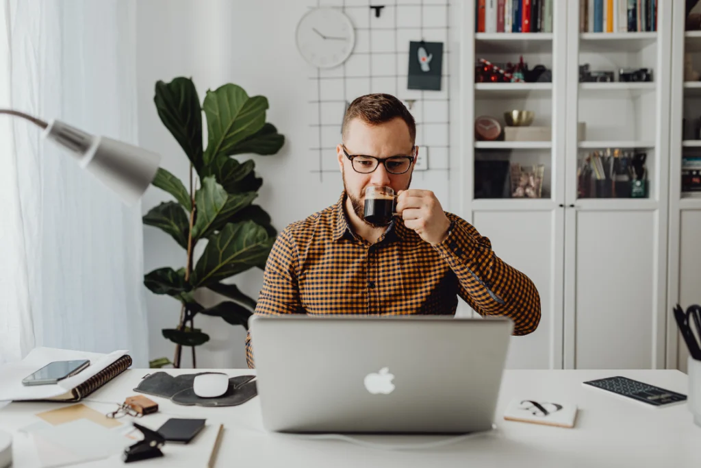 Founder reviews a supplement facility audit checklist on a laptop while drinking coffee, preparing for a virtual inspection.